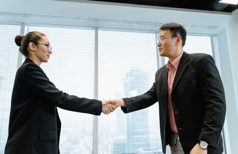 Two people greeting each other with a handshake in an office.