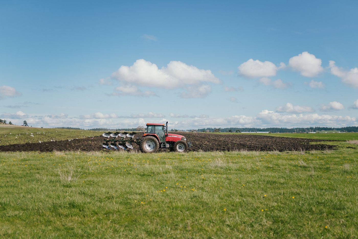 Tractor working in a rural Indiana field beneath a blue sky.